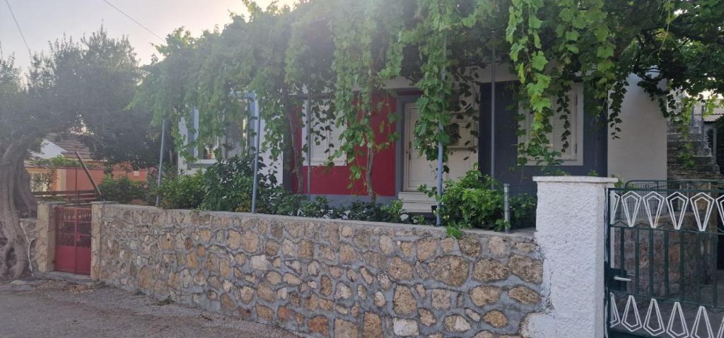 a house with a stone wall and a fence at The Holiday House in Mavráta