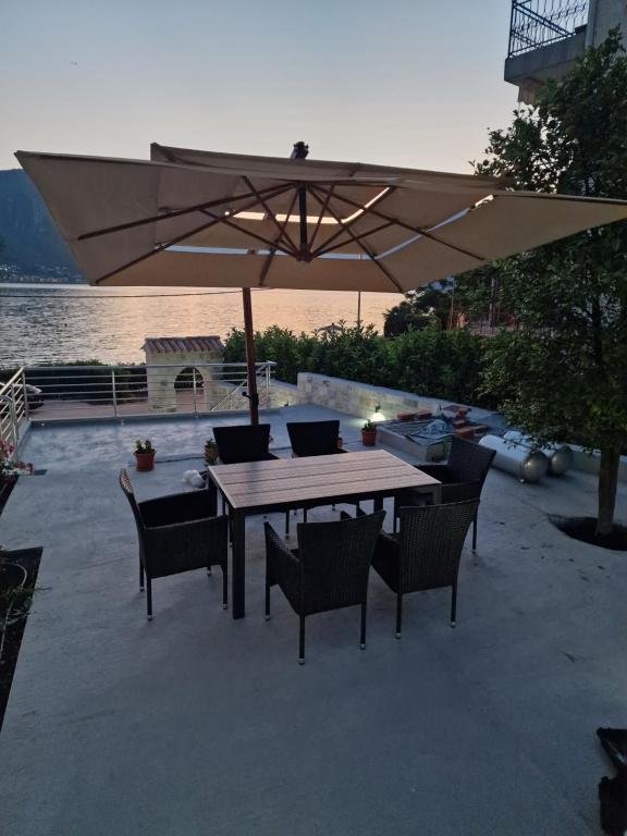 a wooden table and chairs with an umbrella at Waterfront Apartment Petrovina in Kotor
