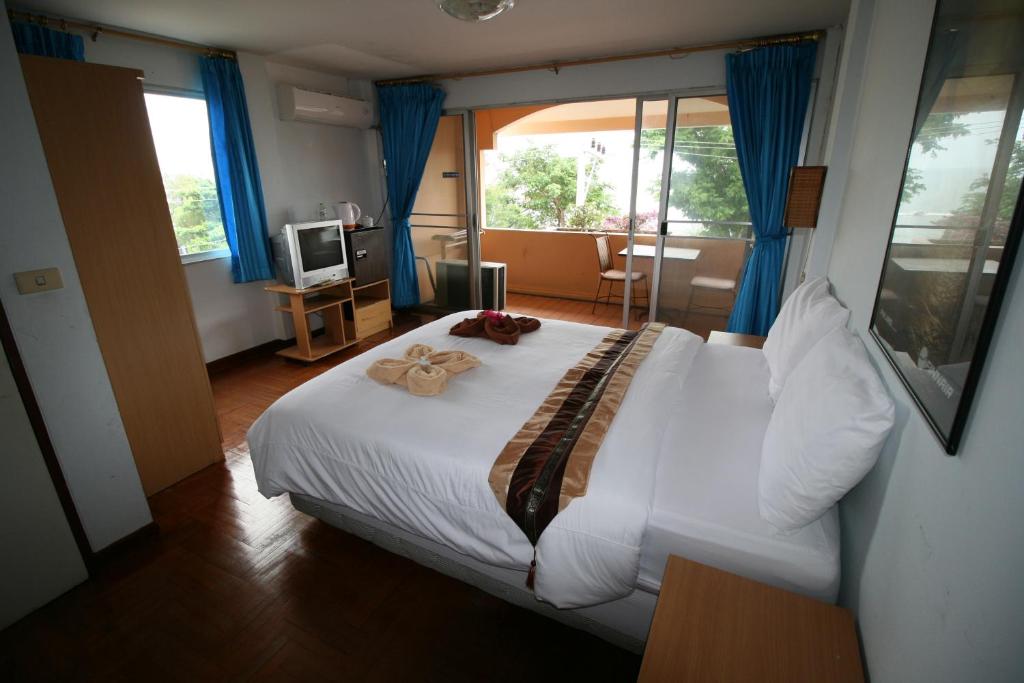 una camera da letto con un grande letto bianco con due rose sopra di Beachfront Hotel Cha Am a Petchaburi