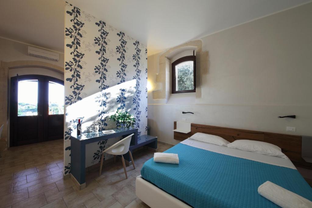 a bedroom with a blue bed and a desk at Casal Sikelio in Cassibile