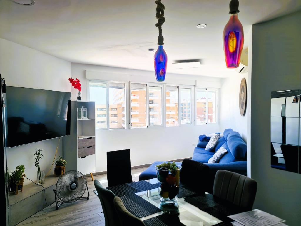 ein Wohnzimmer mit einem blauen Sofa und einem Tisch in der Unterkunft Apartamento Las Mercedes - Playa in Torremolinos