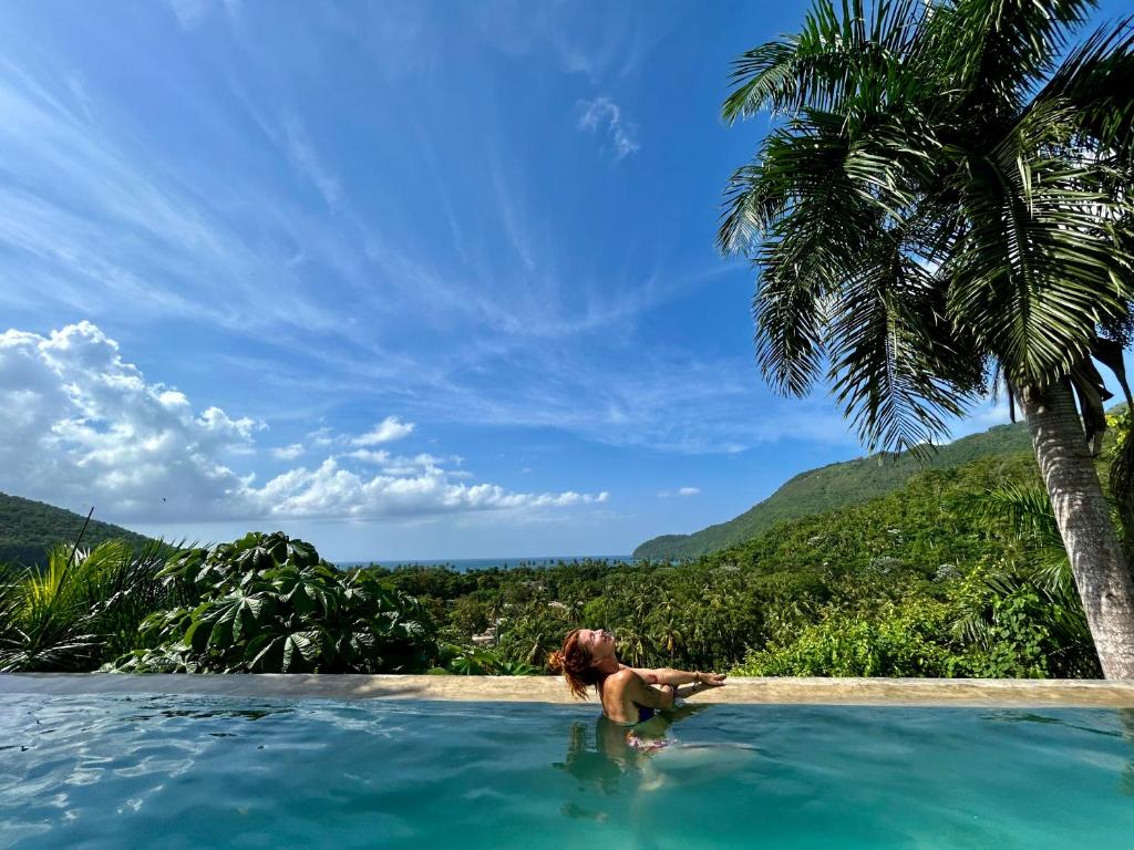 a woman in a infinity pool with a palm tree at ZÂRIA Hotel & Retreat Center in El Valle