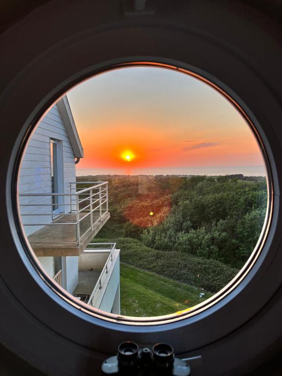 une fenêtre ronde avec vue sur le coucher du soleil dans l'établissement appartement vue mer, à Wimereux
