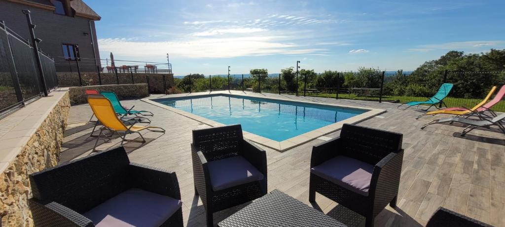 a swimming pool with two chairs and a table at Le petit nid du Quercy in Anglars-Nozac