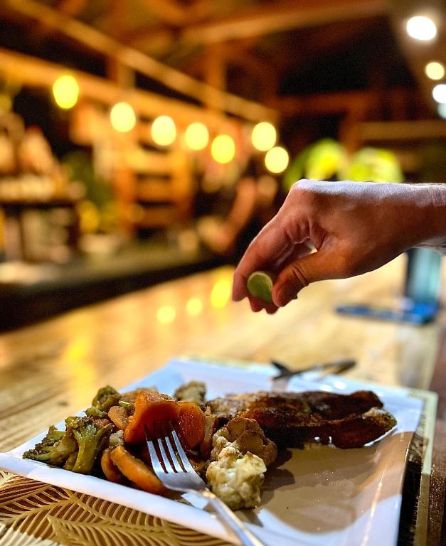 a person holding a lime on a plate of food at ZÂRIA Hotel & Retreat Center in El Valle
