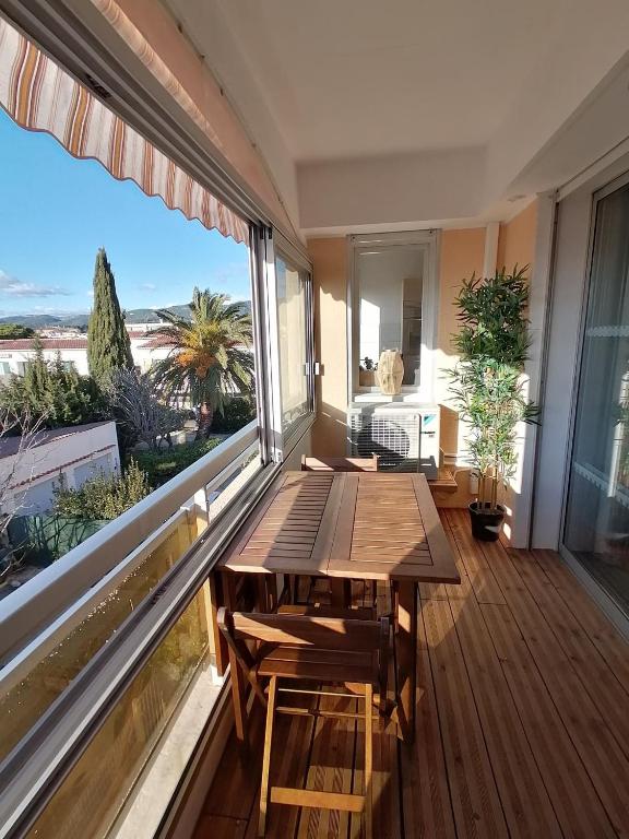 Elle comprend un balcon avec une table en bois et une grande fenêtre. dans l'établissement Idéalement placé ,tout a pied ,parking, à Six-Fours-les-Plages