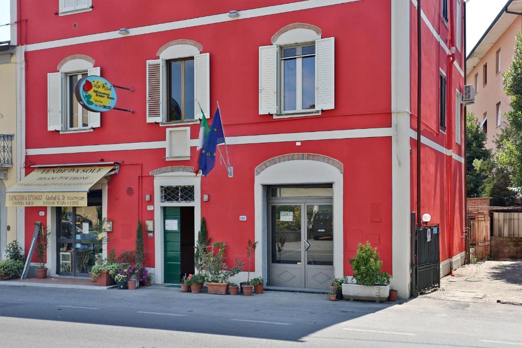a red building with a flag in front of it at Affittacamere La Rosa in Lucca