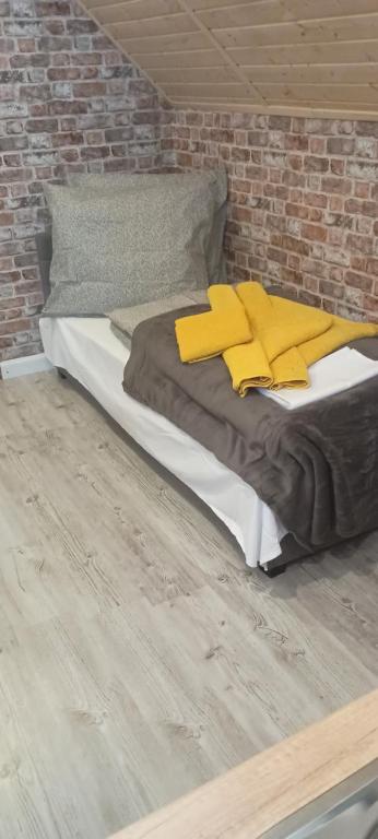 斯维诺乌伊希切Studio Robi 18m2的一张带黄色枕头和砖墙的床
