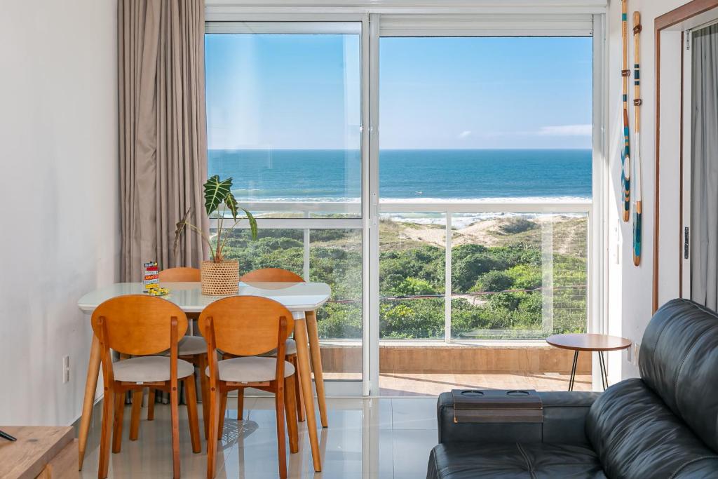 uma sala de estar com mesa e cadeiras e vista para o oceano em Apartamento Vista Mar no Novo Campeche em Florianópolis