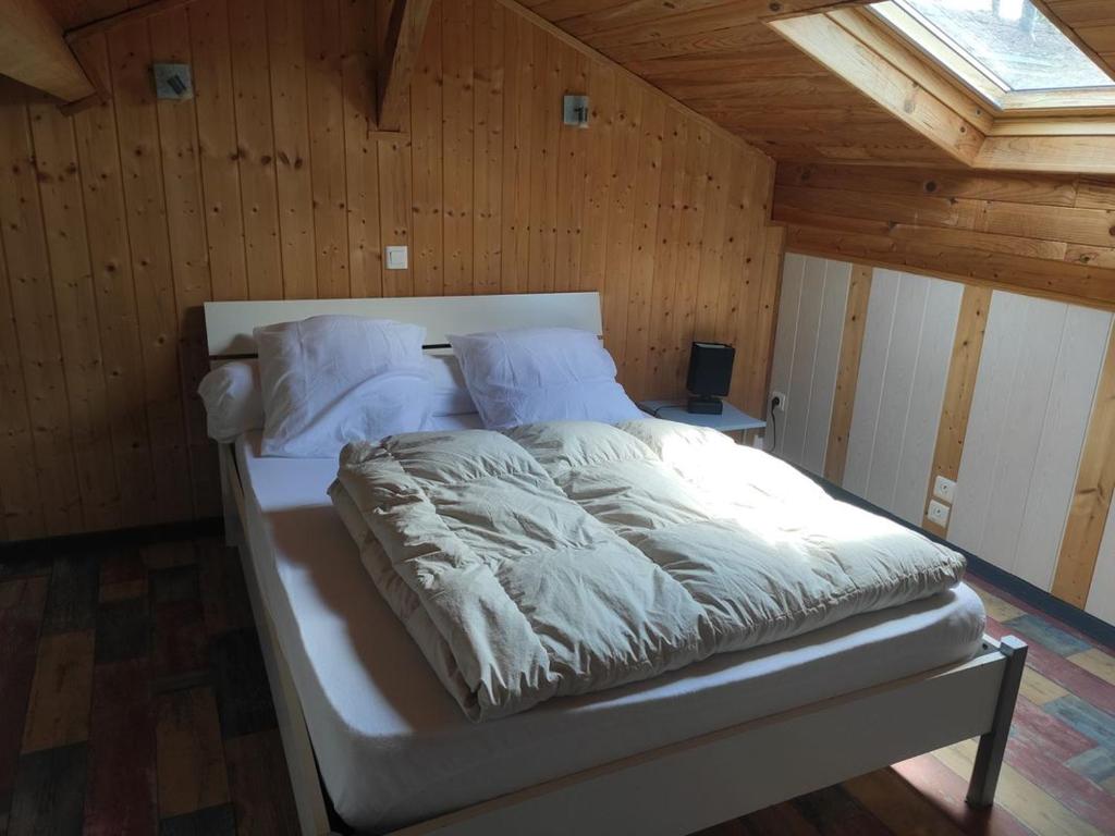a white bed in a room with a wooden ceiling at Petit gite paisible en bord de lac in Saint-Gérons