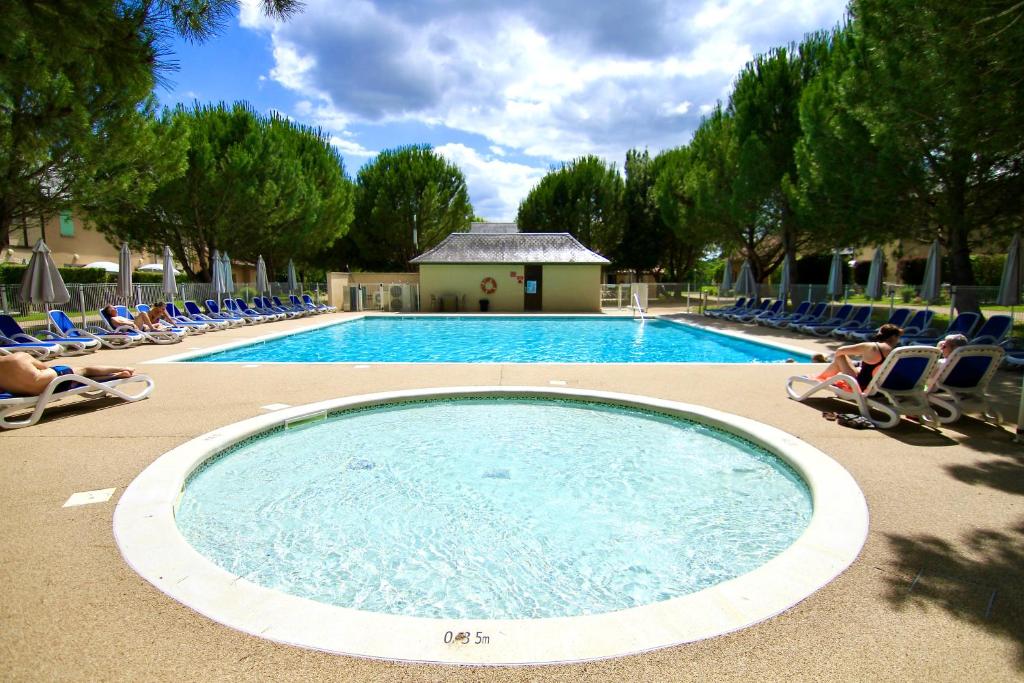 a swimming pool with chairs and people sitting around it at La belle histoire in Montignac