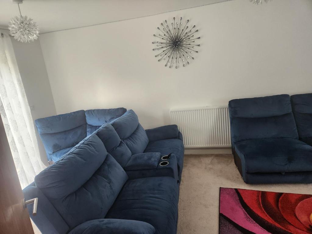 Una sala de estar con un sofá azul y una silla. en Ensuite room, en Ashfordby