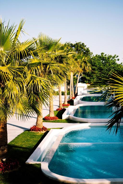 a resort with palm trees and a row of waterfalls at Kallithea Village hotel in Kallithea Halkidikis