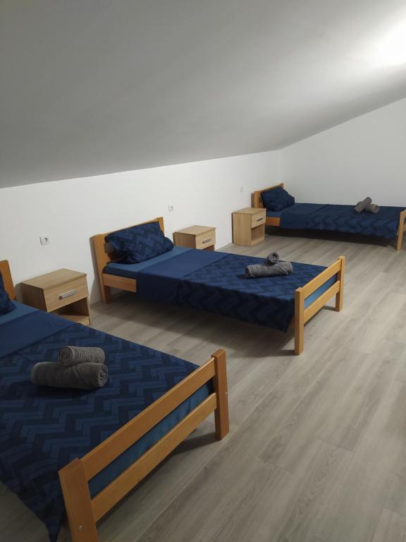 Zimmer mit 3 Betten, blauer Bettwäsche und Holzböden in der Unterkunft Lotus house in Zrenjanin