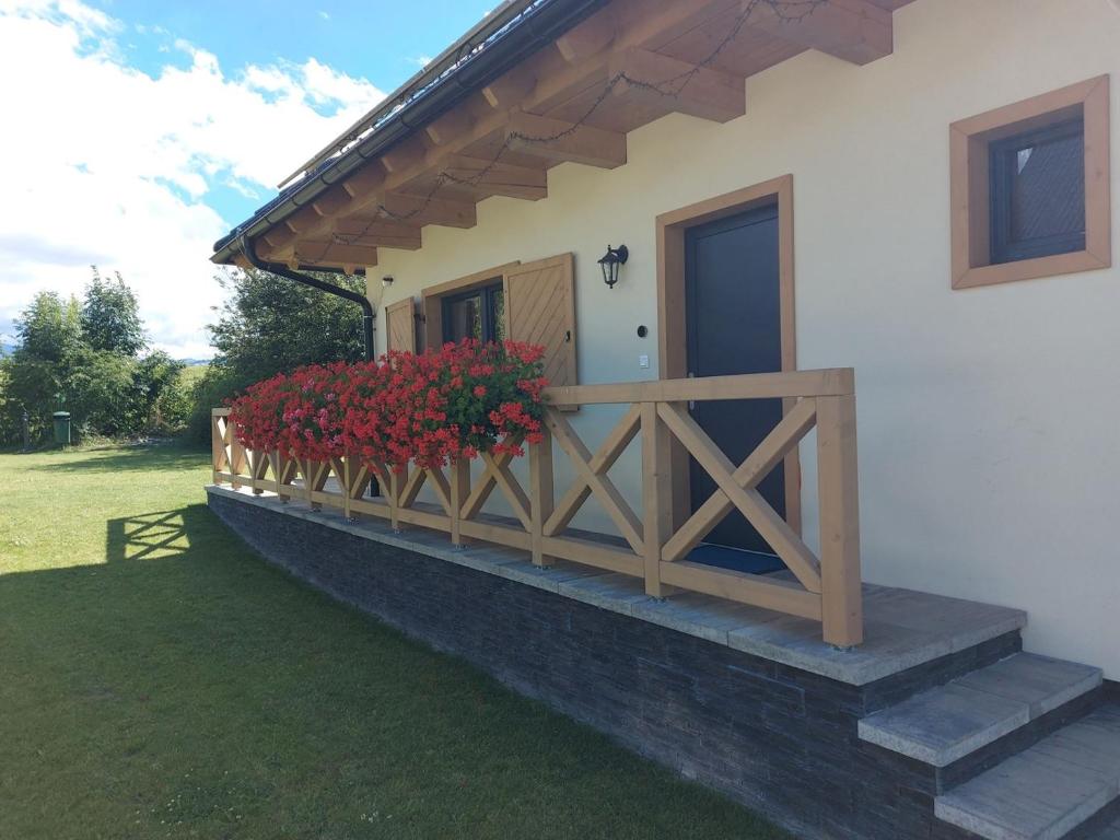 a porch of a house with red flowers on it at CHALUPY TRI GROŠE VLAŠKY in Bešeňová