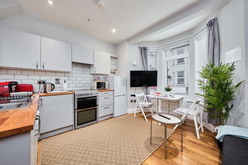 eine Küche mit weißen Geräten und einem Tisch mit Stühlen in der Unterkunft Princess Green 1 - Portrush by the Sea in Portrush