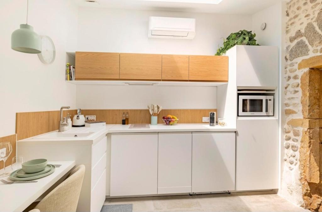 une cuisine avec des armoires blanches et un réfrigérateur blanc dans l'établissement Aux Voûtes de Granit - 10 mn Lyon, à Pierre-Bénite