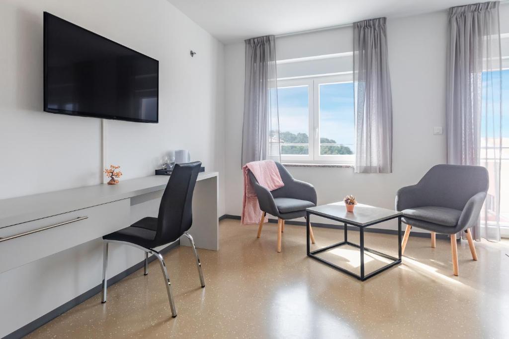 a living room with two chairs and a table and a television at Villa Grace in Rovinj