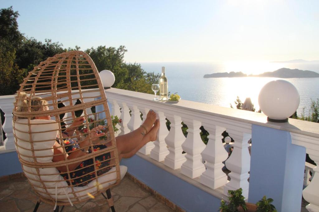 a person sitting on a balcony with a basket of wine bottles at Villa Bettina 2nd floor in Afionas