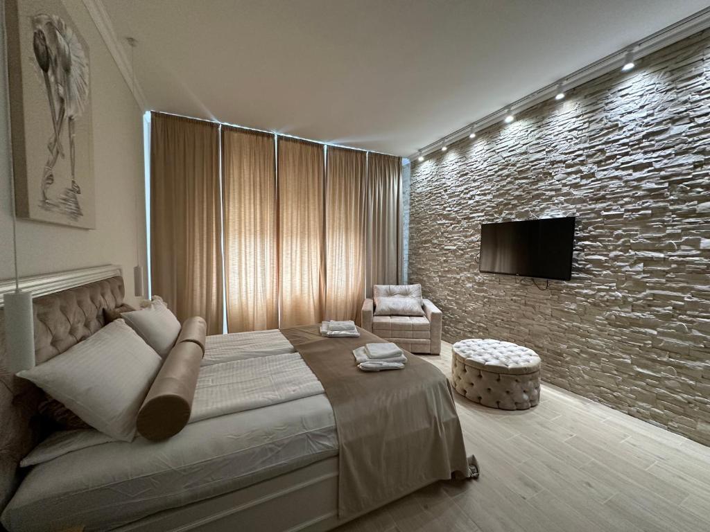 a bedroom with a large bed and a stone wall at Apartman Modena Novi Sad in Novi Sad