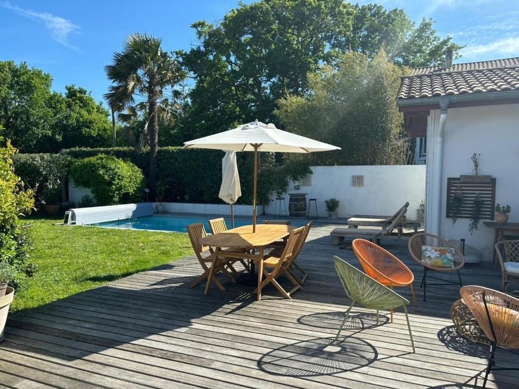 une terrasse en bois avec une table et un parasol dans l'établissement BIDART villa proche des plages et commodités, au calme, piscine chauffée, à Bidart