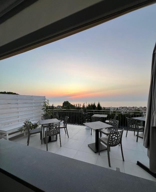 a balcony with tables and chairs and a sunset at Villa Mimosa Florital - Free Private Parking On site & in Tropea in Santa Domenica
