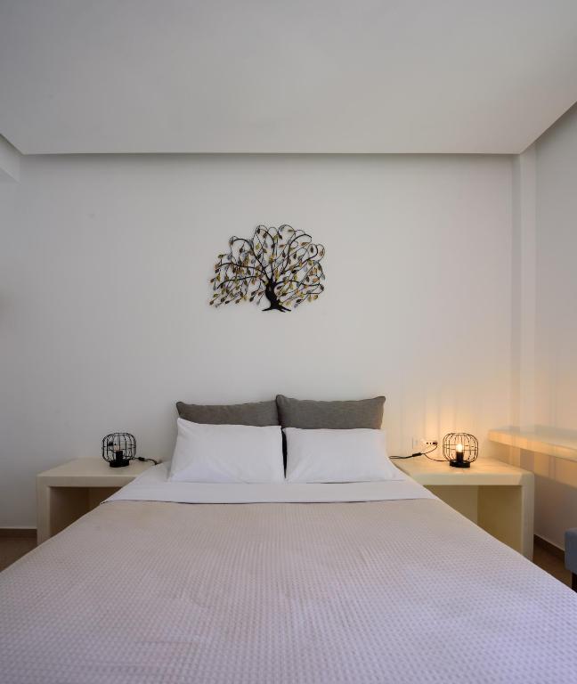 a bedroom with a white bed with a tree clock on the wall at Armonia in Kamari