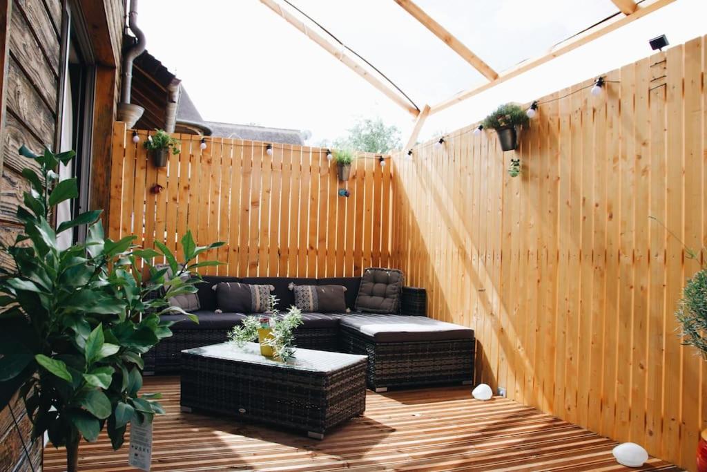 une terrasse avec un canapé et une clôture en bois dans l'établissement Sentier du Clos, à Nemours