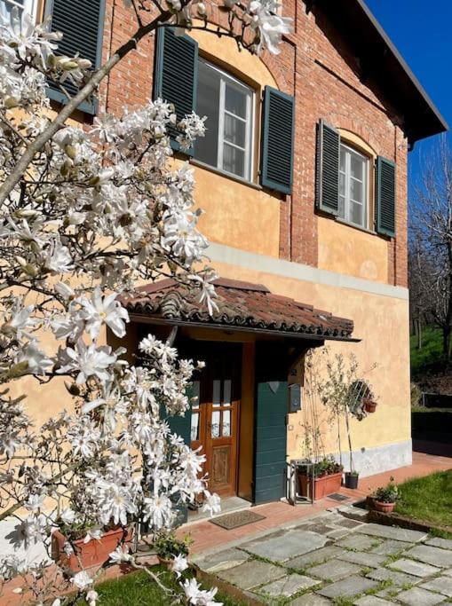 a building with a flowering tree in front of it at Locanda del Glis glis in Castelletto d'Orba