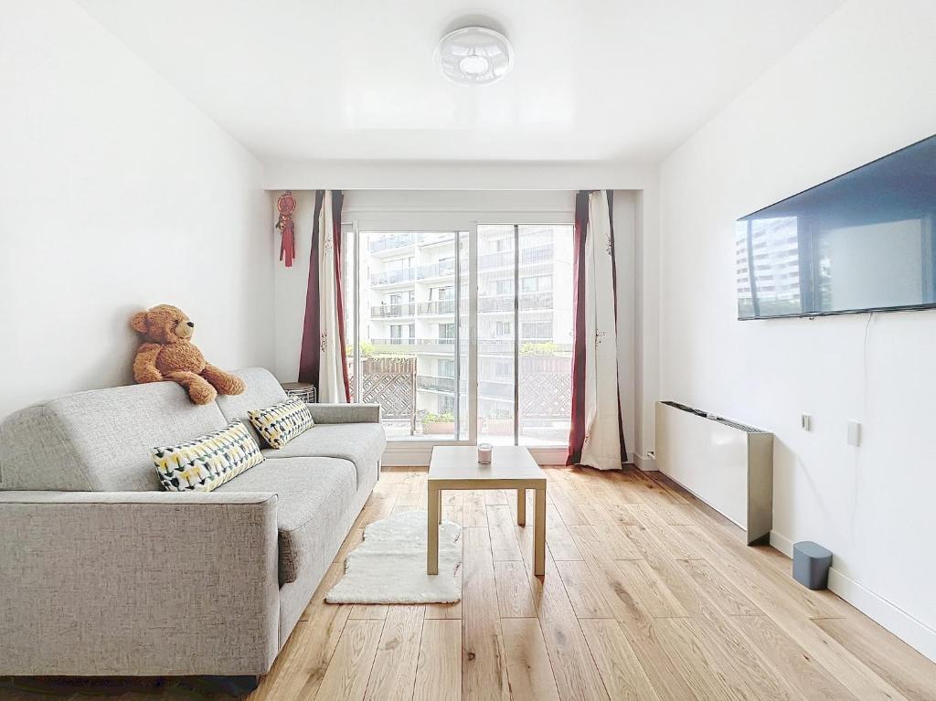 - un salon avec un ours en peluche assis sur un canapé dans l'établissement 114 - Paris Appartement Rénové de Luxe pour 4 Personnes, à Paris
