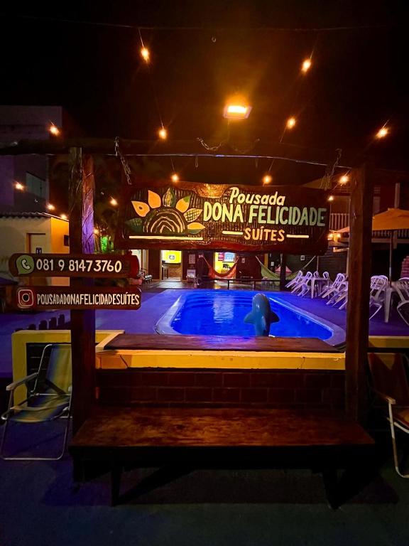 a swimming pool in front of a casino at night at Pousada Dona Felicidade Carneiros in Tamandaré