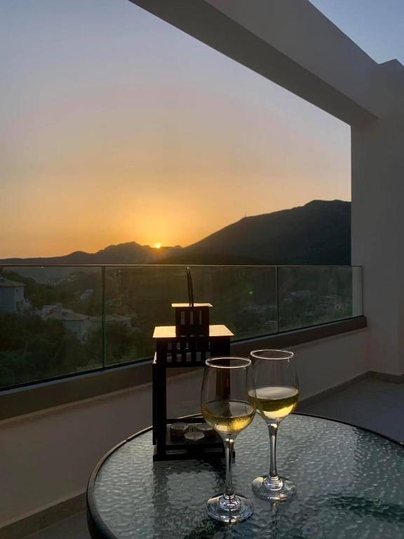 two glasses of white wine sitting on a table with the sunset at LefkoParga Luxury Suites in Parga