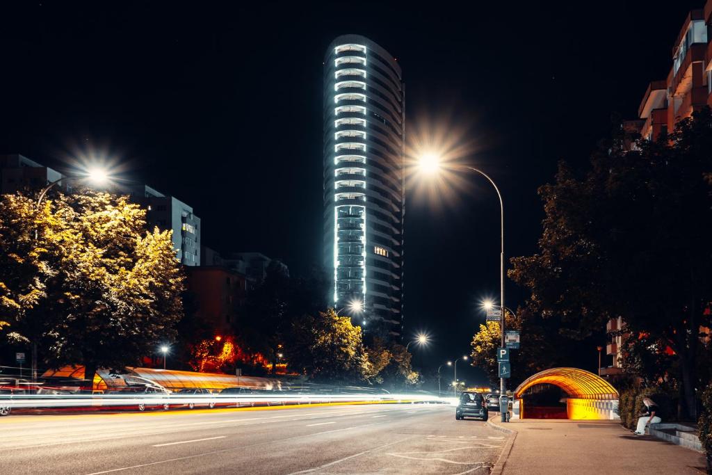 a tall building at night with a street light at Cremene Tower ApartHotel in Cluj-Napoca