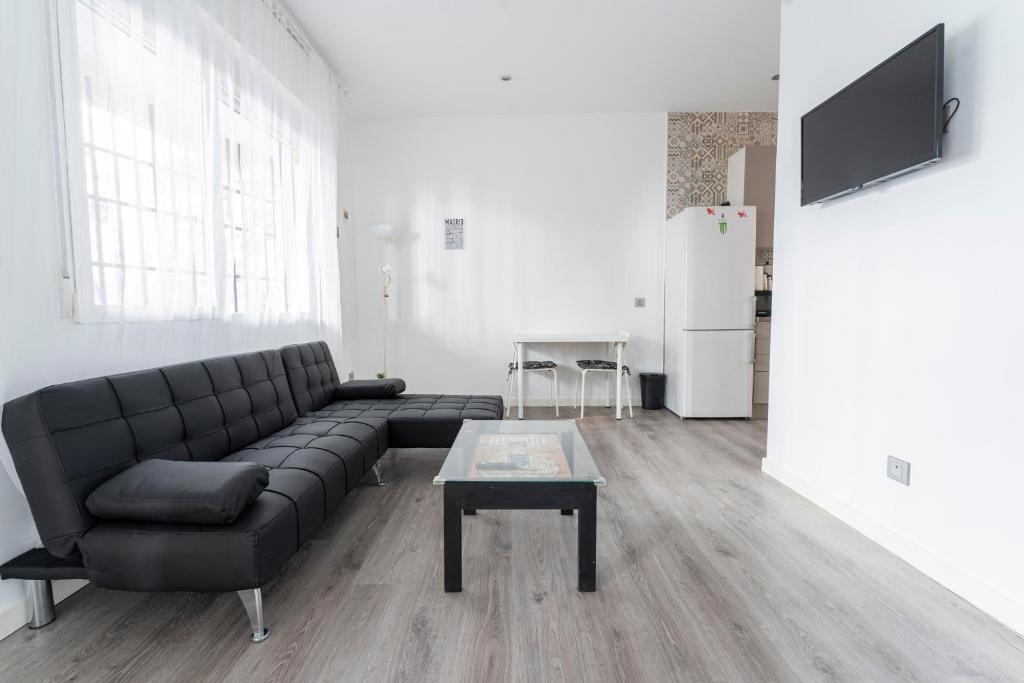 un soggiorno con un divano nero e un tavolo di Hogar en Calle Lavapiés a Madrid