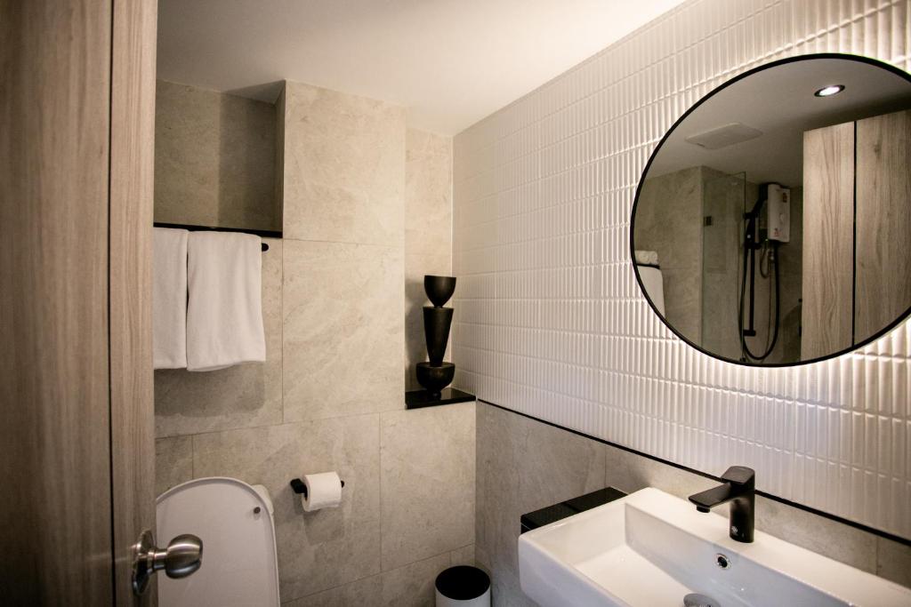 A compact bathroom with a vessel sink, round mirror and walk-in shower.