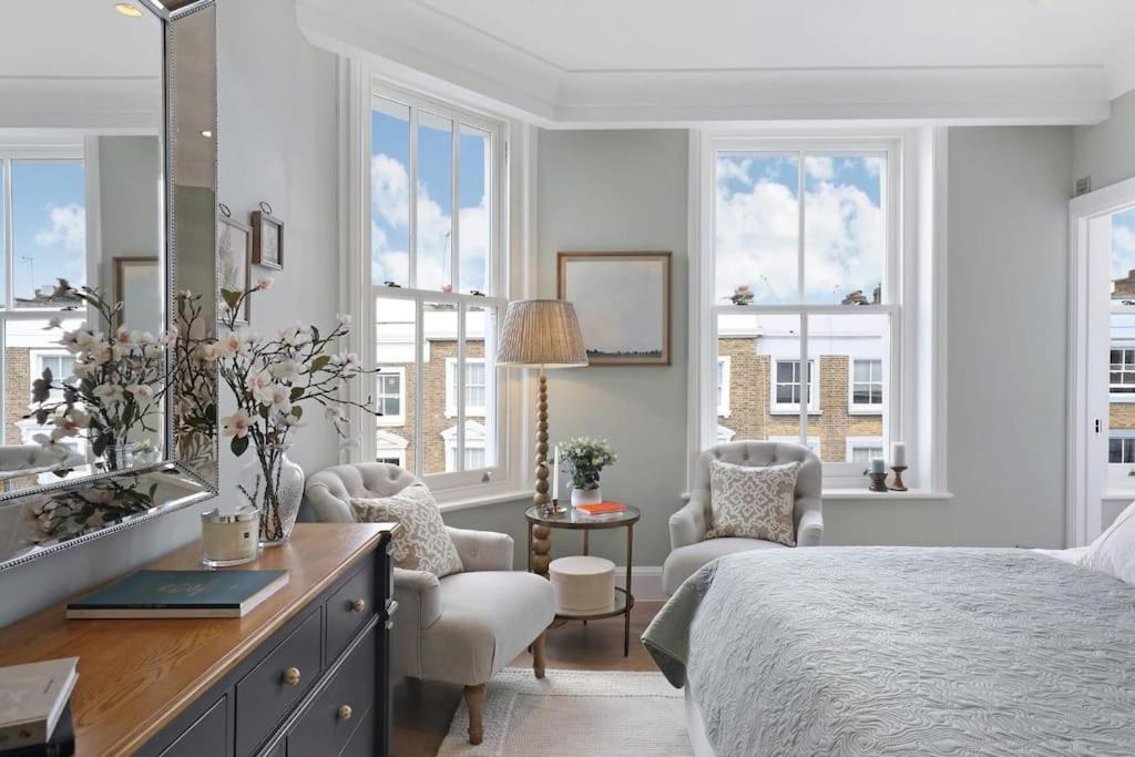a bedroom with a bed and a sink and windows at 3 Bed Corner House Portobello Rd in London