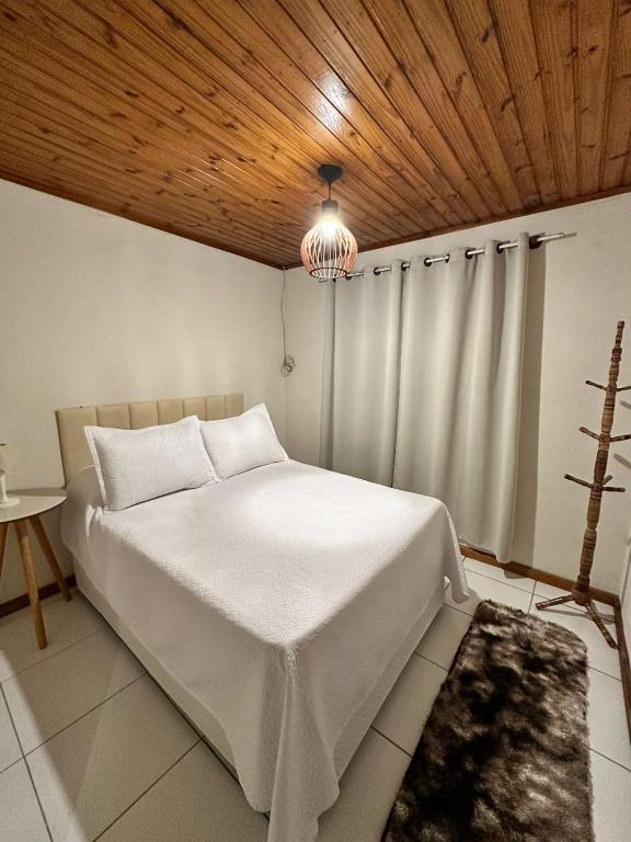 een slaapkamer met een wit bed en een houten plafond bij Residencial Casuarina Monte Verde in Camanducaia