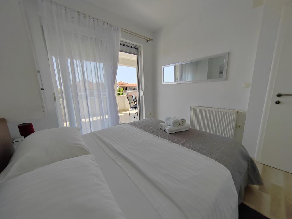 Una cama blanca con un animal de peluche encima. en Mila Apartments Zadar, en Zadar