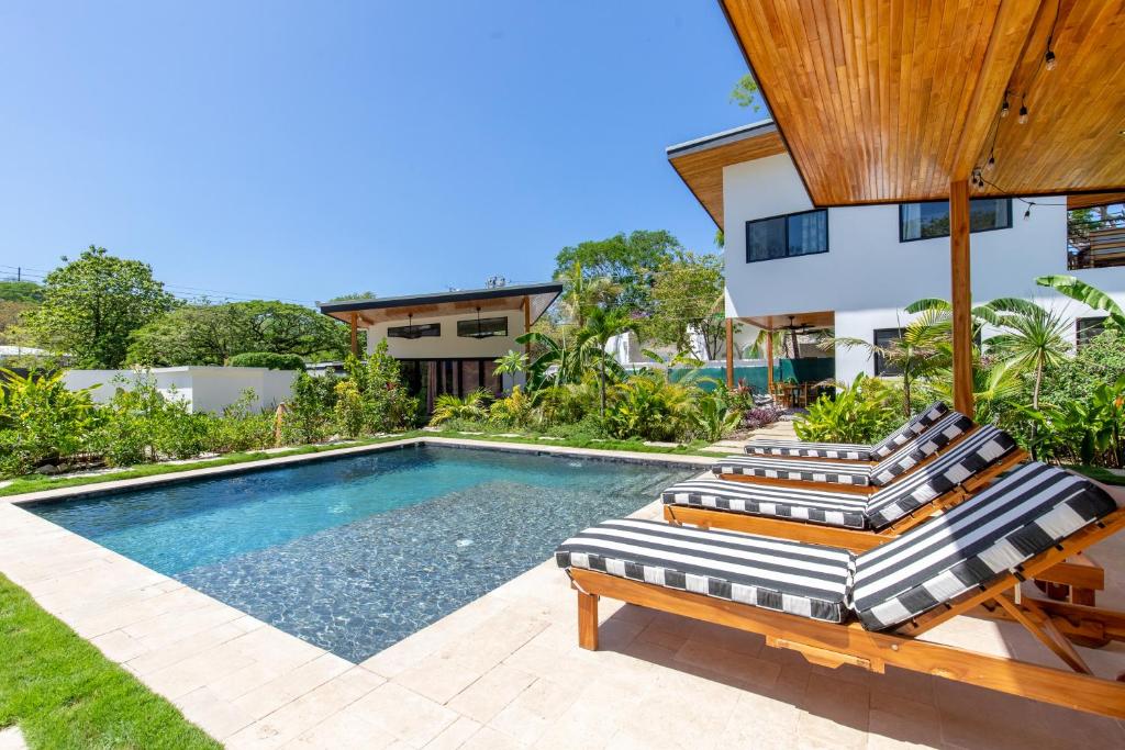 - une piscine avec 2 chaises longues et une maison dans l'établissement La Joya de Nosara, à Playa Pelada