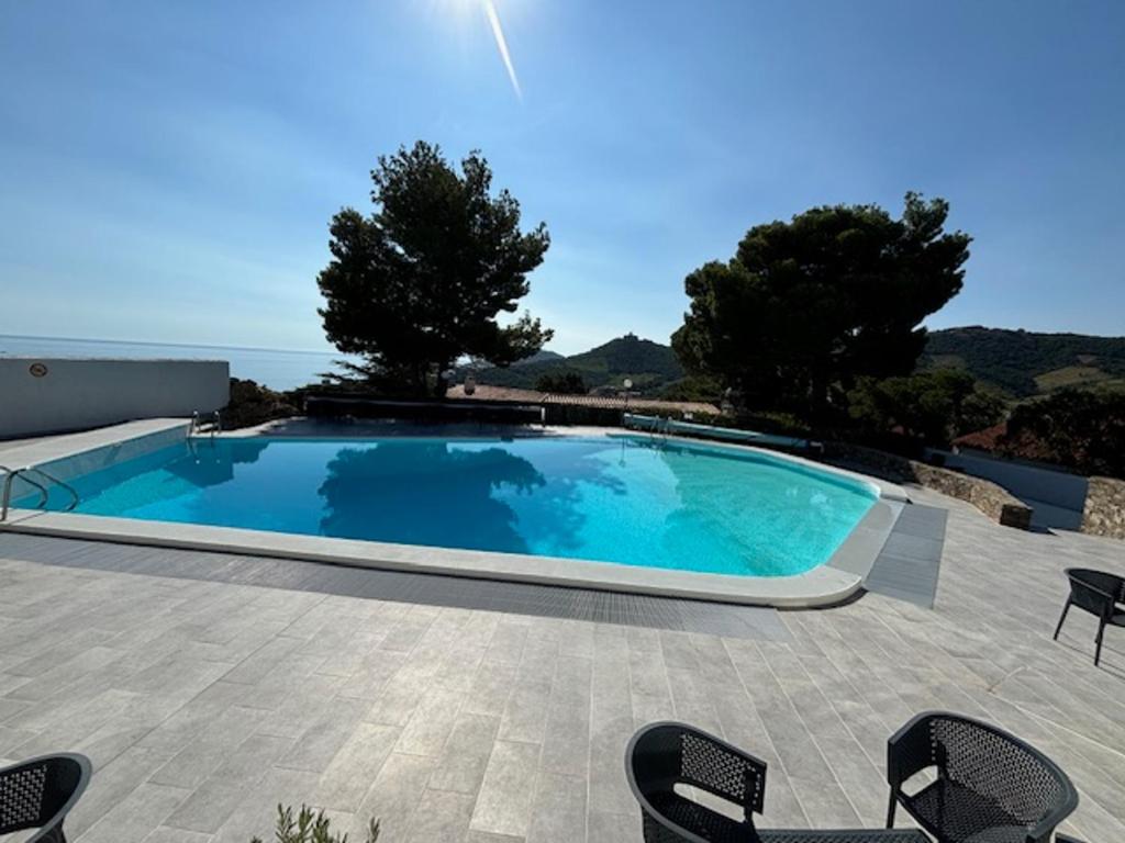 a large swimming pool with chairs on a patio at Charmante maison sécurisée avec piscine à Collioure - FR-1-309-454 in Collioure