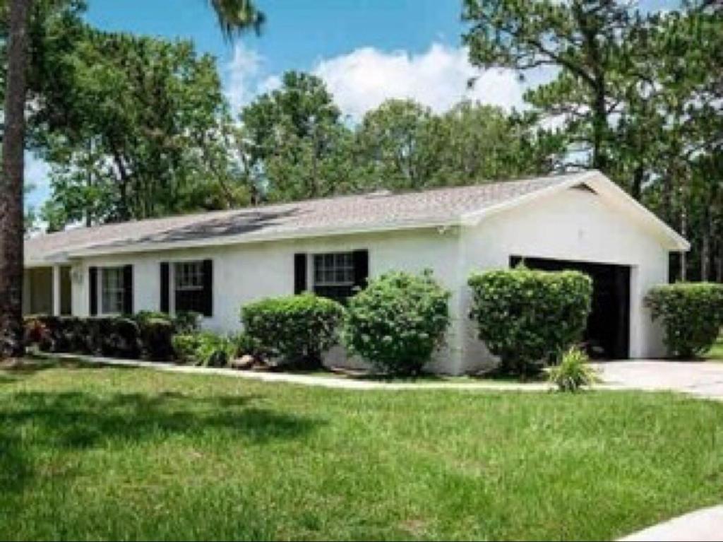 a white house with bushes and trees at 2 homes within 5 miles of each other, one on Lake in Lutz