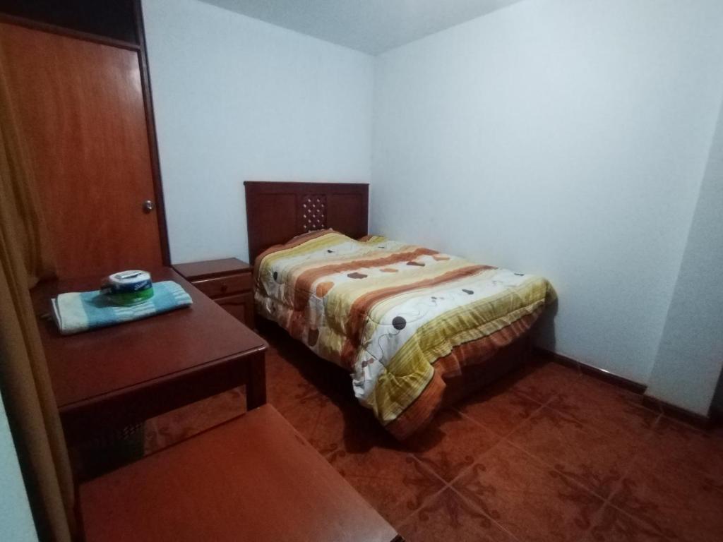 ein kleines Schlafzimmer mit einem Bett und einem Tisch in der Unterkunft Hospedaje Hipito in Nazca