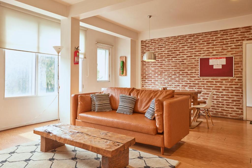 a living room with a brown couch and a brick wall at Ananya Apartments Phase 1 in Kathmandu