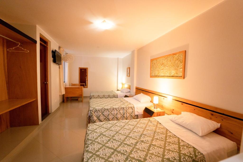 una camera d'albergo con tre letti e una televisione di Hostal Los Balcones II a Nazca