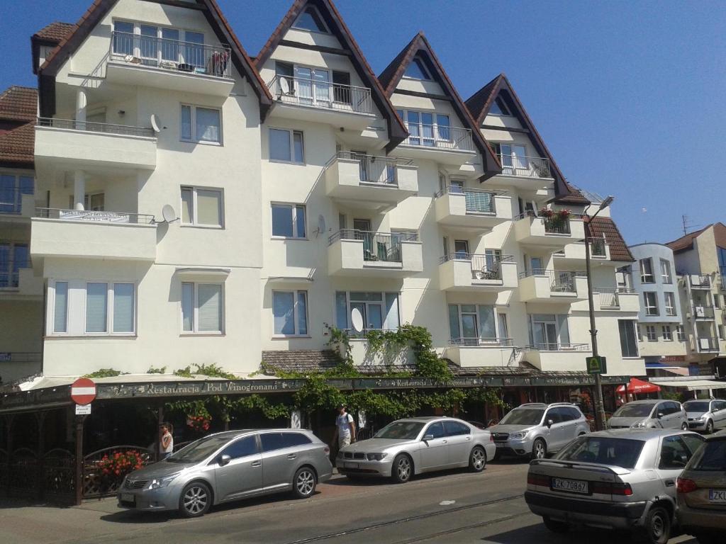 a large white building with cars parked in front of it at Apartament Portowy z garażem, ul Towarowa in Kołobrzeg