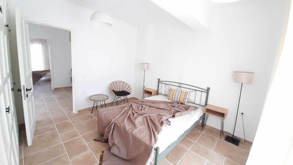 a white bedroom with a bed and two chairs at Rozas house in Benitses