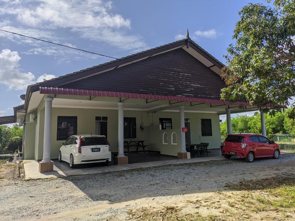 a small house with two cars parked in front of it at Homestay Ayah Ngah Marang in Marang