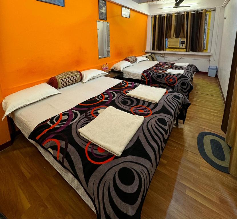 four beds lined up in a room with orange walls at The Golden Lodge Varanasi in Varanasi