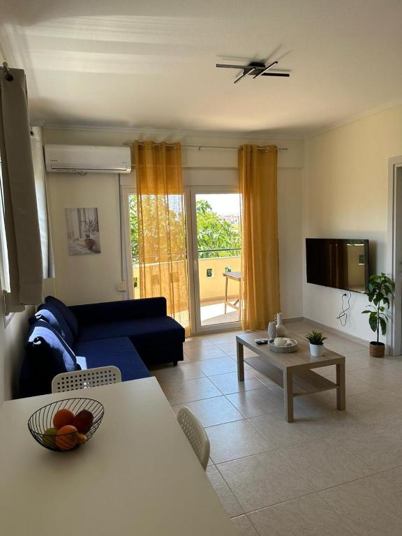 a living room with a blue couch and a table at Dimar3 Seaside Apartment in Paralia Dionysiou