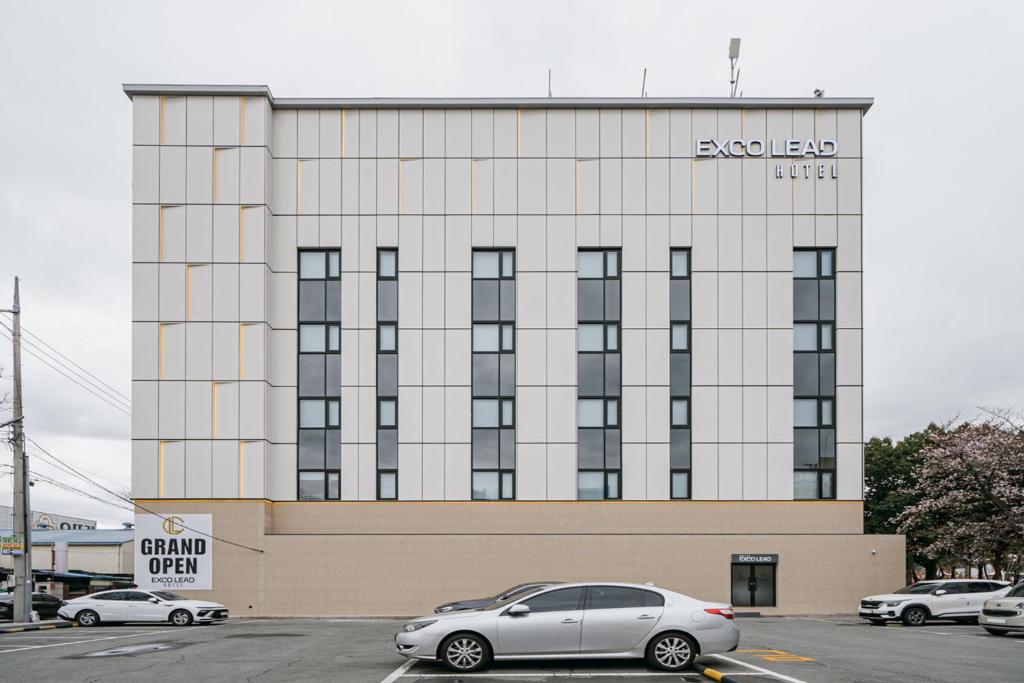 a building with cars parked in a parking lot at Daegu Exco Lead Hotel in Daegu